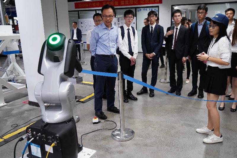 政制及内地事务局局长聂德权（左一）今日（七月三十日）与学生参观位于东莞的松山湖国际机器人产业基地，听取人员简介机器人运作。